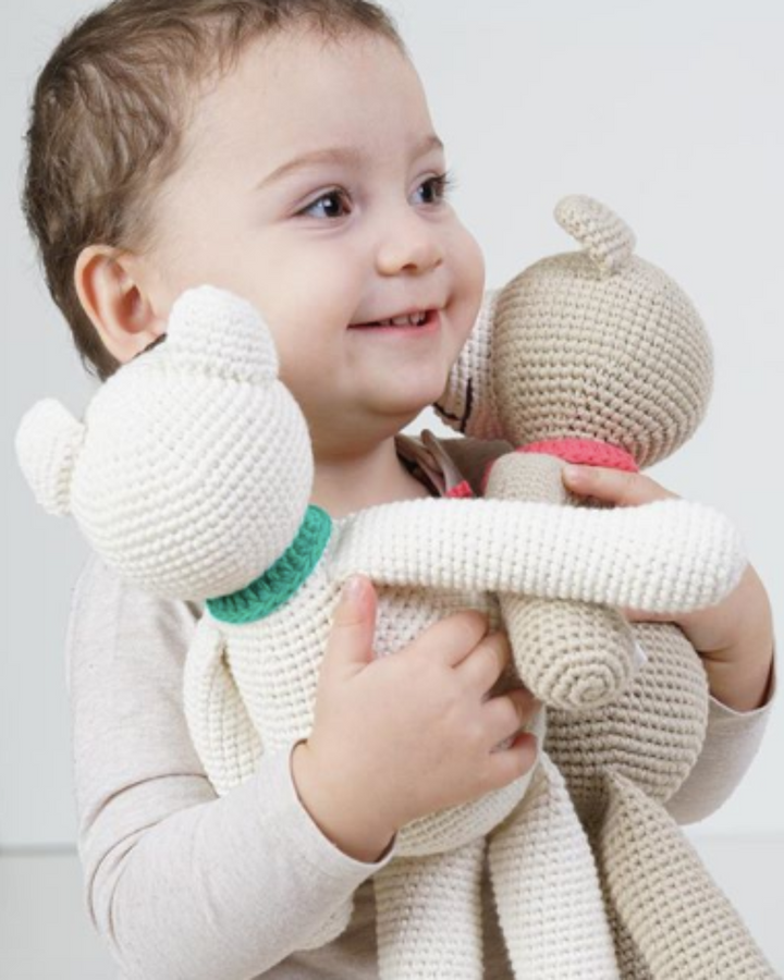תינוקת מחזיקה בדובי סרוג חברותי - שמחה ואהבה במתנה אחת