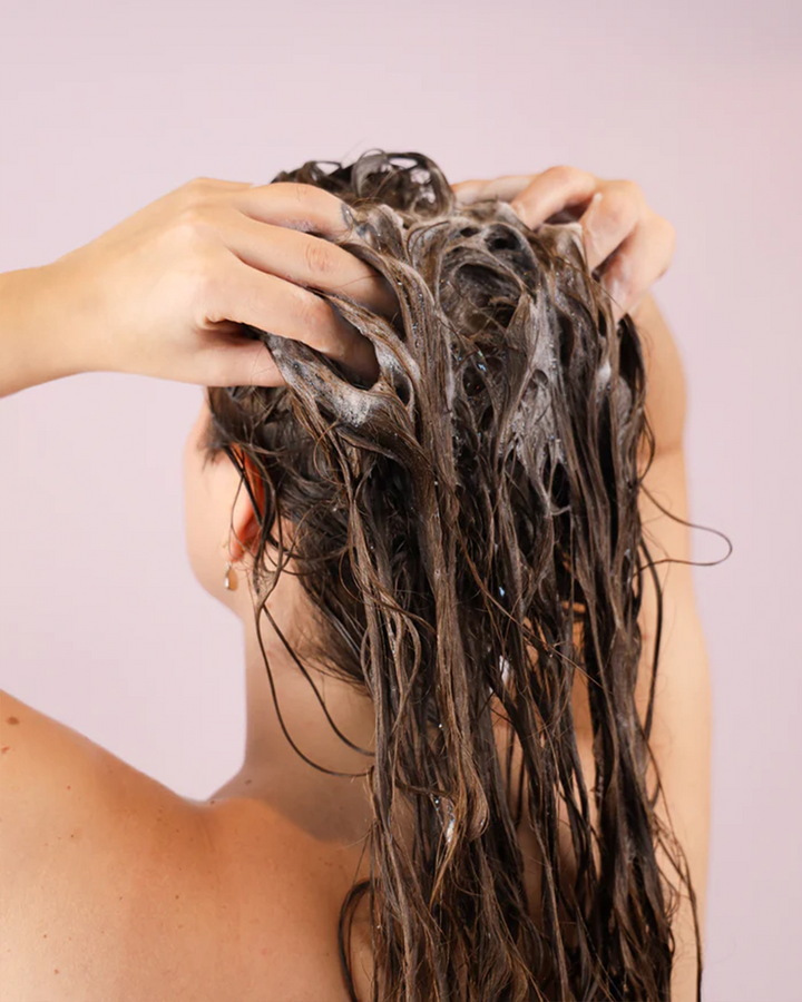 אישה מורחת שמפו לשיער צבוע , שמפו מזין המעניק לחות ומגן על הצבע