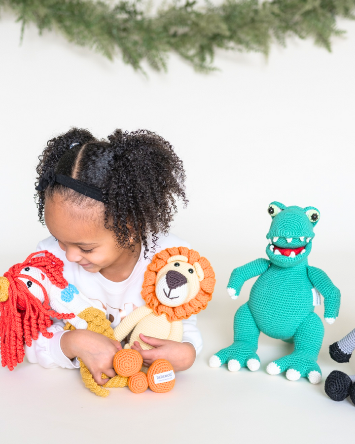 ילדה משחקת עם בובות סריגה שונות כולל דינוזאור ואריה